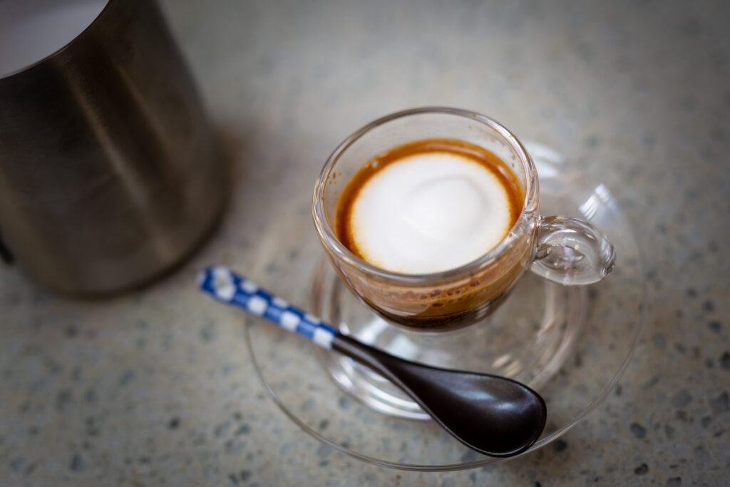 A traditional macchiato, with a white dollop of foam on top of espresso, pictured from above.
